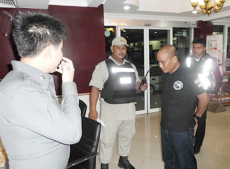 Kampan Wiangnon (front right) is brought in for questioning after allegedly attempting to use his badge to harass a woman on Walking Street.